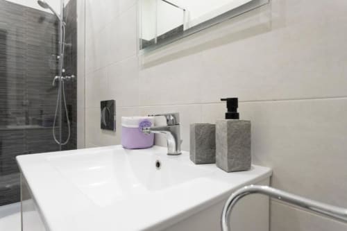 Moderno bagno nella villa Pia Domus di Exclusive Domus Gaudia a Roma, con lavabo bianco, finiture grigie e doccia in vetro