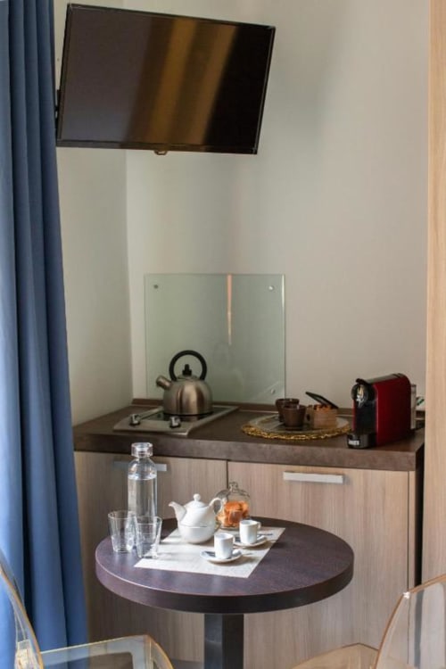 Angolo cottura Pia Domus con tavolo rotondo, piano cottura, bollitore e TV a parete dell'hotel Roma
