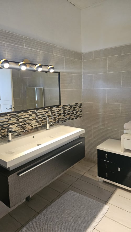 Modern bathroom in Chambre Baobab at Kaz Kafe with dual vanity, tiled walls, and contemporary fixtures