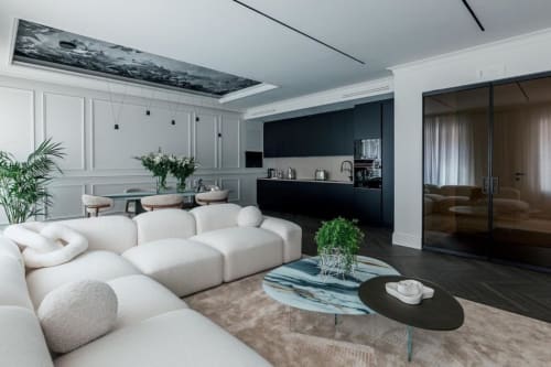 Lussuoso soggiorno della villa esclusiva Domus Gaudia Roma con divano bianco curvo, cucina nera e tavolo in marmo