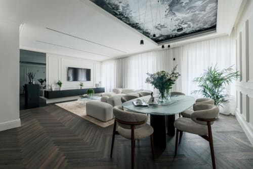 Zona living lussuosa e moderna a Domus Gaudia Roma con tavolo da pranzo, arredi neutri, piante e soffitto con lucernario