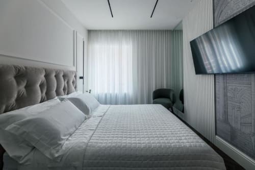 Camera moderna presso Exclusive Domus Gaudia Roma con testata trapuntata, biancheria bianca, TV a parete e tende leggere