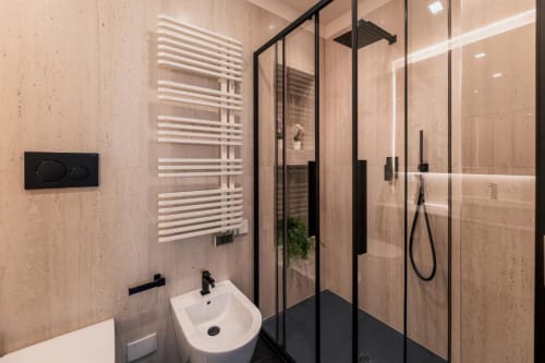 Bagno moderno presso Exclusive Domus Gaudia Roma con doccia walk-in, scaldasalviette bianco e rivestimenti in marmo beige