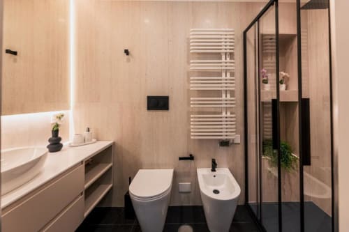 Bagno moderno nella villa romana con piastrelle nere e beige, sanitari bianchi, scaldasalviette e doccia in vetro