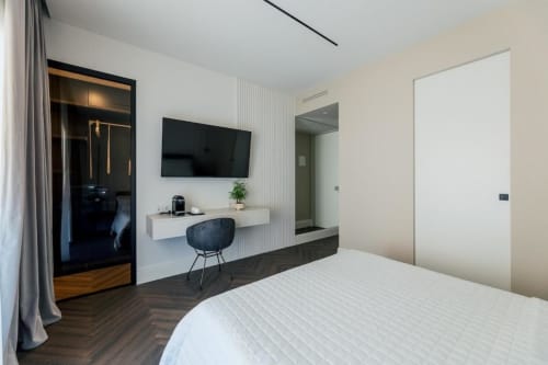 Camera moderna presso Exclusive Domus Gaudia Roma con letto, TV a muro, scrivania e accesso al bagno privato