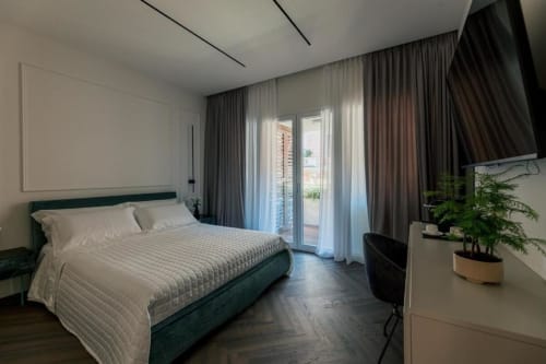 Camera da letto moderna presso l'Exclusive Domus Gaudia Roma con letto verde, accesso al balcone, tende e pianta in vaso