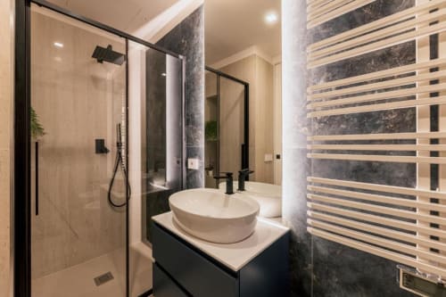Bagno di lusso moderno a Exclusive Domus Gaudia Roma con doccia a pioggia, lavabo a calice, scaldasalviette e marmo scuro