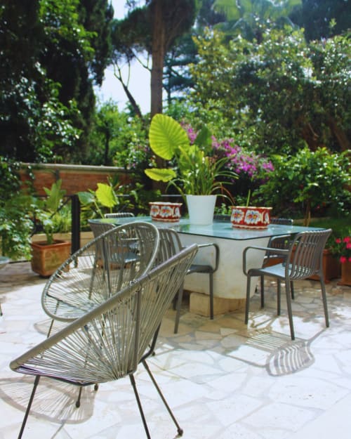 Lush garden terrace at EppyTime Rome with woven chairs, dining table, potted flowers, and ivy-covered walls