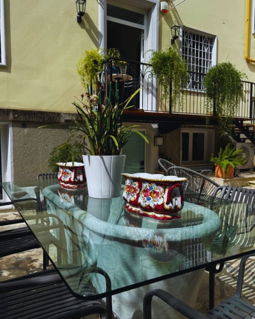 Outdoor dining area at EppytimeRome with glass table, decorative cushions, potted plants, and yellow building facade in Roma