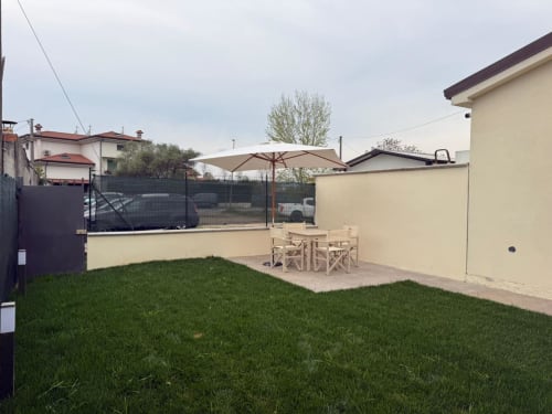 Patio del giardino della villa a Mistral Holidays a Marina di Carrara con prato, ombrellone e arredamento da pranzo