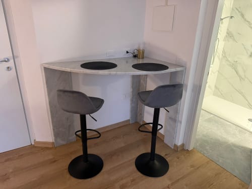 Moderno bancone cucina con due sgabelli neri e piano cottura elettrico nell'appartamento di Marina di Carrara