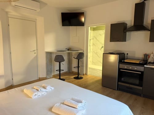 Monolocale moderno a Marina di Carrara con cucina, bancone bar, letto con asciugamani e ingresso con vista giardino