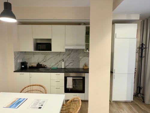 Cocina moderna en apartamento de Ruzafa con armarios blancos, encimera negra, backsplash de mármol y zona de comedor