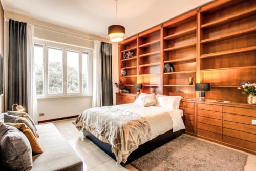 Camera da letto in appartamento Borghese a Roma con scaffalature in legno, letto matrimoniale, vista sul giardino e servizi moderni