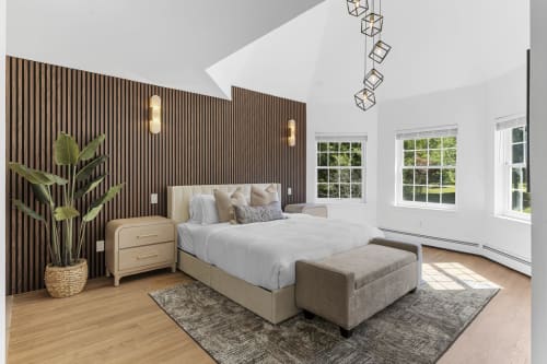 Modern bedroom at Malkita Homes in Highland Mills with wood accent wall, neutral bedding, and large windows overlooking
