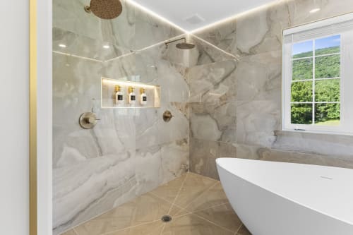 Luxurious marble bathroom at Malkita Homes with freestanding soaking tub, walk-in shower, and mountain views