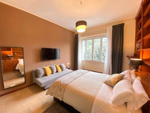 Ampia camera da letto in appartamento romano con vista sul giardino, arredamento moderno, TV e comoda zona living