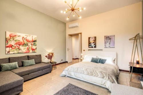 Appartamento Borghese Green a Roma - camera da letto moderna con zona living, divano grigio, letto matrimoniale e vista giardino