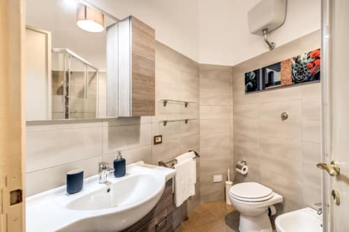 Bagno moderno in appartamento Borghese verde nel centro di Roma con lavandino, wc, doccia e rivestimento in piastrelle neutre