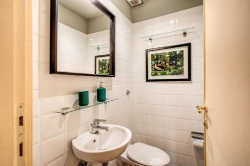 Bagno moderno dell'appartamento Downtown Srl a Roma con pareti in piastrelle bianche, arte botanica incorniciata, lavabo da appoggio e verde