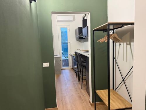 Corridoio moderno con pareti verdi, pavimenti in legno e appendiabiti presso Mistral Holidays Marina di Carrara