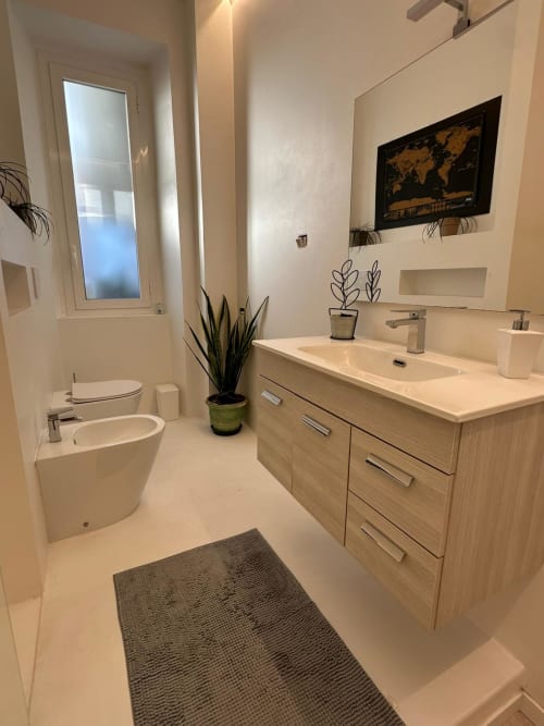 Modern bathroom in Aparthotel Bentivoglio Catania with wooden vanity, white fixtures, and plant decor
