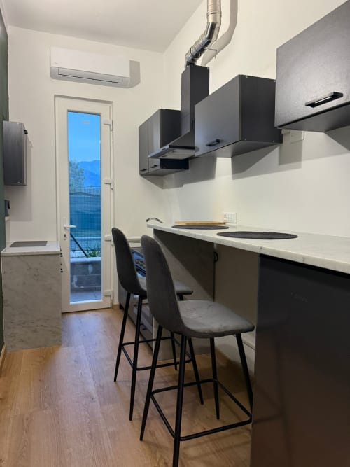 Moderna cucina con ripiani neri, bancone per sedute e vista mare all'appartamento Mistral Holidays a Marina di Carrara