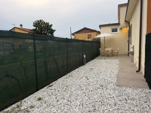 Patio privato del giardino dell'appartamento Mistral Holidays a Marina di Carrara con zona ghiaia, ombrellone e sedute