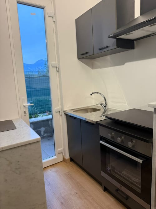 Cucina moderna con elettrodomestici neri, lavello e porta che si affaccia sul giardino presso l'appartamento Mistral Holidays a Marina di