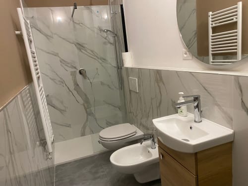 Moderno bagno con doccia in marmo, wc, bidet e lavabo con vanità in legno nell'appartamento Mistral Holidays, Marina di Carrara