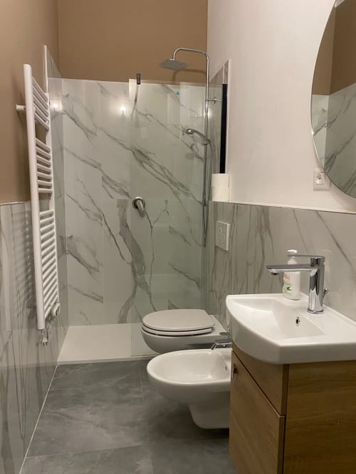 Bagno moderno presso Mistral Holidays Marina di Carrara con doccia in marmo, lavabo bianco, bidet e toilette