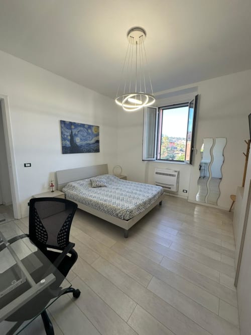 Modern bedroom at Aparthotel Bentivoglio, Catania with bed, desk, pendant light, and sea view window
