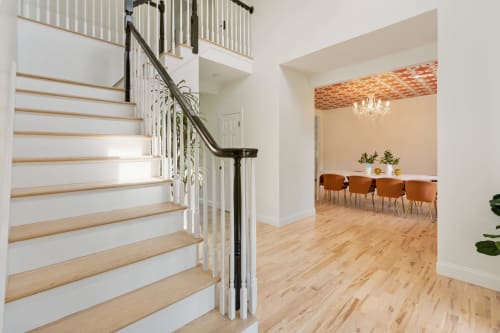 Modern staircase with wood steps and metal railing at Malkita Homes in Highland Mills, dining area visible