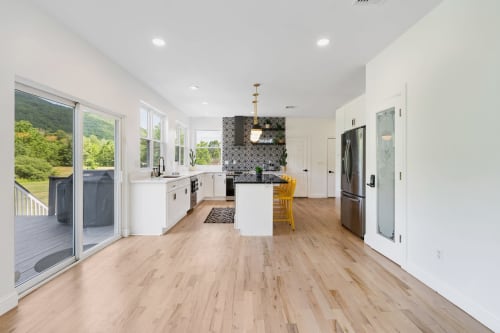 Modern kitchen with white cabinets, island seating, hardwood floors, and views of Highland Mills landscape