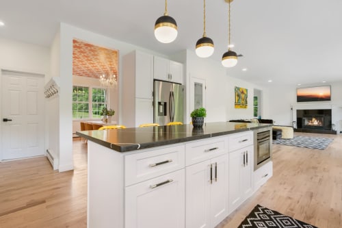 Modern Highland Mills kitchen with white cabinetry, black countertops, stainless steel appliances, and pendant lighting