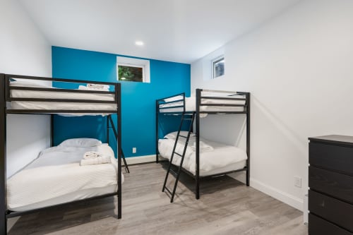Modern shared bedroom at Malkita Homes Highland Mills with two black bunk beds, white bedding, and vibrant blue accent wall