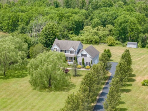 Two-story home at Malkita Homes in Highland Mills surrounded by mature trees and pastoral landscape