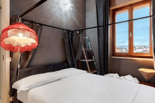 Letto a baldacchino moderno con lampada rossa e frangia a Mistral Holidays, Marina di Carrara, con vista sulla città e arredamento scuro
