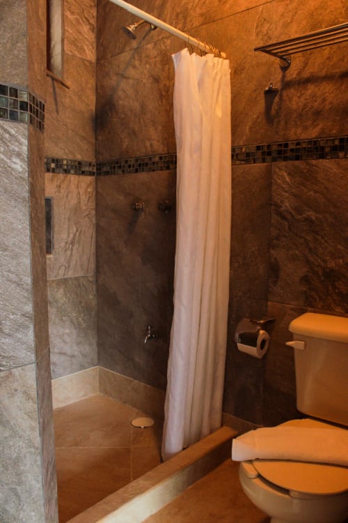 Baño moderno de la villa Casa Tucán en hotel Tucan Village, Bacalar, con ducha tipo walk-in, azulejos beige e inodoro