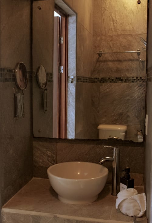 Baño moderno en villa Tucan Village, Bacalar con lavabo de cerámica blanca, espejos climatizados y ducha con azulejos de piedra