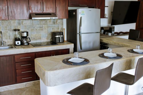Cocina y comedor modernos en la villa Casa Tucán de Tucan Village, Bacalar, con electrodomésticos de acero inoxidable y vistas al lago