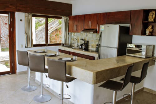 Moderna cocina y comedor de la villa Casa Tucán en Tucan Village, Bacalar, con vistas al lago y barra.