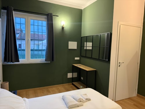 Modern bedroom at Mistral Holidays, Marina di Carrara, with green walls, wooden floors, and contemporary furnishings