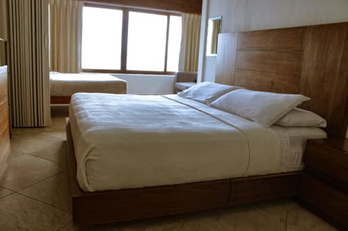 Dormitorio moderno en villa Tucan Village, Bacalar, con mobiliario de madera, ropa de cama blanca y vistas al lago a través de grandes ventanales