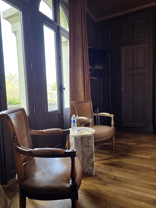 Elegant sitting area at Le Castel B&B Bayeux with leather armchairs and cathedral view through tall windows