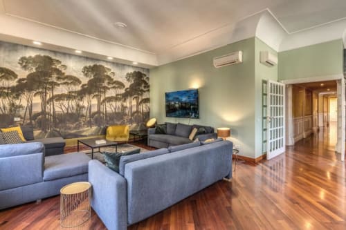 Soggiorno Penthouse Imperial Panorama a Roma con divano blu moderno, murale naturalistico, pavimenti in legno e vista sui monumenti della città