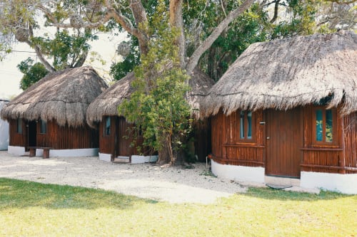 Bungalows con techo de palma de la Aldea Tucan, arquitectura de madera entre árboles en Bacalar, México