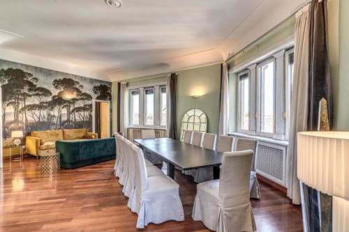 Zona living e pranzo della Penthouse Imperial Panorama con pavimenti in legno, finestre panoramiche e viste sui monumenti di Roma