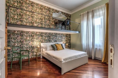Camera da letto della Penthouse Imperial Panorama a Roma con carta da parati floreale, zona lavoro in soppalco, parquet e design moderno