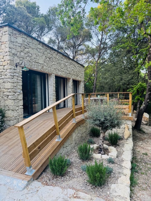 Maison en pierre avec terrasse en bois et balustrade, entourée d'arbres à la Maison Terre de Lune B&B à Mondragon
